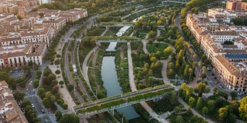 Vista aérea de una ciudad española moderna con abundante infraestructura verde y espacios naturales restaurados, simbolizando la sostenibilidad.